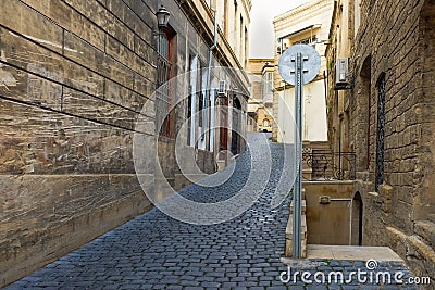 Perspective view to empty ascending narrow small street with traditional old black cobblestones pavement Stock Photo