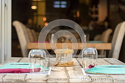 Perspective view of a wooden table with chairs, glasses and plates outdoors in a Greek taverna in Hydra, Greece Stock Photo