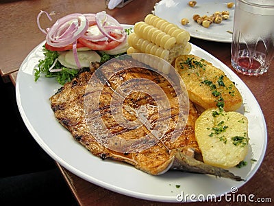Peruvian dish - fried fish fillet with vegetables, onion, corn, boiled potatoes Stock Photo