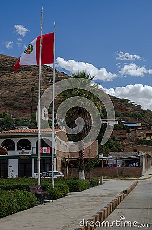 peruvian flag hoisted on mast in street surrounded by houses in andean town Stock Photo