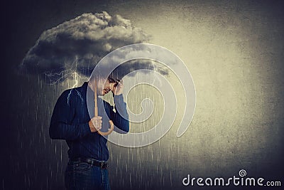 Pessimistic man, standing under rain, suffering anxiety as holding an umbrella thunderstorm cloud over head. Concept of memory Stock Photo