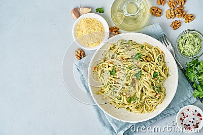 Pesto pasta, bavette with walnuts, parsley, garlic, nuts, olive oil. Top view, copy space, blue background. Stock Photo