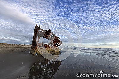 Peter Iredale shipwreck under a partly cloudy sky. Stock Photo