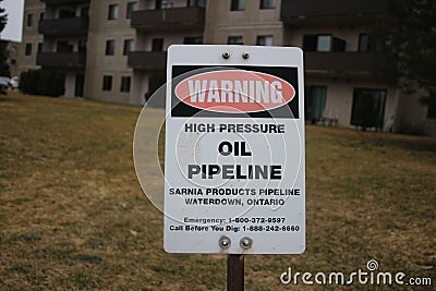Petroleum pipeline warning sign in green grassy meadow. Editorial Stock Photo