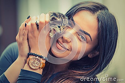 Pets Care.Young woman holding cat home. Closeup striped Cute cat in woman hands. Focus on girl, kitty out of focus Stock Photo