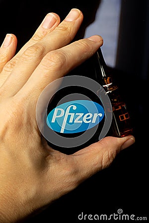 Pfizer coronavirus vaccine pharmaceutical corporation. Logo and hand with vaccine Editorial Stock Photo