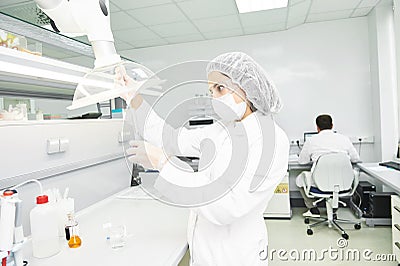 Scientific researcher holding flask with liquid solution and dropper Stock Photo