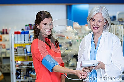 Pharmacist checking blood pressure of customer in pharmacy Stock Photo