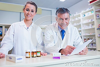 Pharmacist holding a prescription next to his trainee Stock Photo