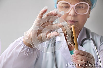 Pharmacist, scientist, doctor holds a comb and removes hair for a test of biological material for DNA, pathology, blue virtual Stock Photo