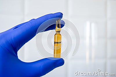 Pharmacist, scientist or researcher holds in his hand, dressed in blue glove, ampoule with medicine, pharmacological agent, poison Stock Photo