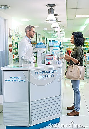 Pharmacists are educated to recognize signs and symptoms of diseases. a mature pharmacist assisting a young woman in a Stock Photo