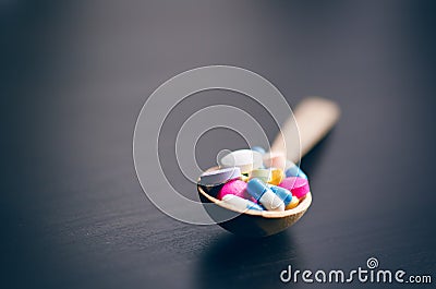 Pharmacy background on a black table with measuring tape. Tablets on a wooden spoon. Pills. Medicine and healthy. Close up of caps Stock Photo