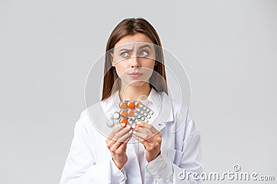 Pharmacy, healthcare workers, insurance and hospitals concept. Thoughtful and skeptical female doctor in white scrubs Stock Photo