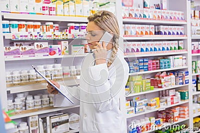 Pharmacy intern phoning while reading clipboard Stock Photo