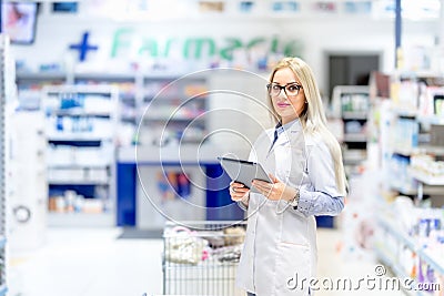 Pharmacy scientist using tablet in pharmaceutical field. medical details with blonde pharmacist Stock Photo