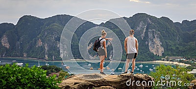 Two foreign tourists stand on the top of the hill overlooking island of phi phi and the sea passenger ship with mountain Editorial Stock Photo