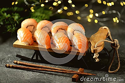 Philadelphia homemade sushi rolls and nigiri sushi with wild salmon on decorative sleigh, christmas background. Stock Photo