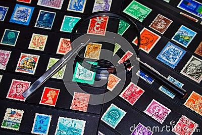 Philately magnifying glass and tweezers to see stamp collection Editorial Stock Photo