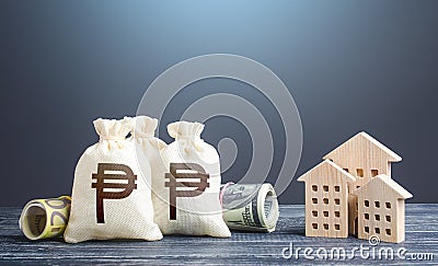 Philippine peso money bags and residential buildings figures. Investments in real estate. Taxes. Mortgage loan. Financing Stock Photo