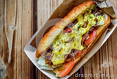 Philly cheese steak sandwich with meat, vegetables, cheese and sause in box on wooden table Stock Photo