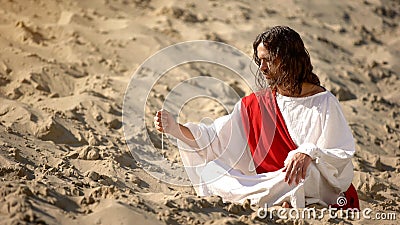 Philosopher pouring sand from hand in desert, reflecting on life and time Stock Photo