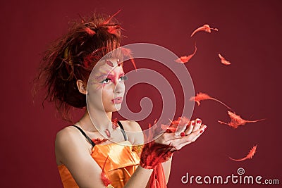 Phoenix. Young girl portrait and flying feathers. Woman holds a feather in hands. Stock Photo