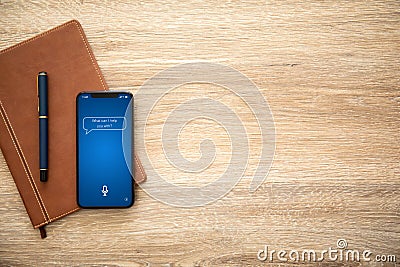 Phone with app personal assistant on screen and notebook Stock Photo
