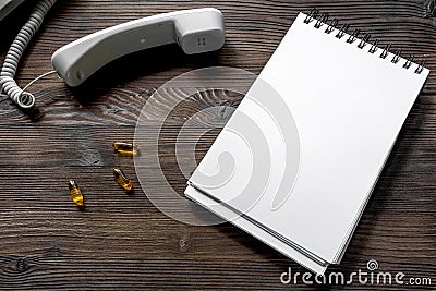 Phone handset, oills and notebook on dark wooden desk top view call doctor mock up Stock Photo