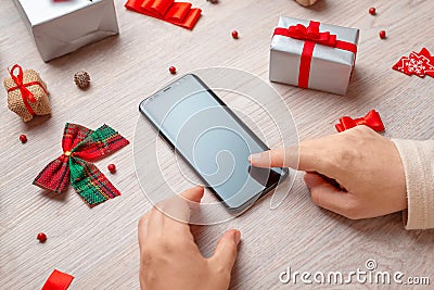 Phone mockup surrounded by Christmas decorations and gifts on wooden table Stock Photo