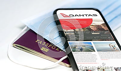 Phone with the Qantas australian airlines app on the screen lying over a protective mask and a passport Editorial Stock Photo