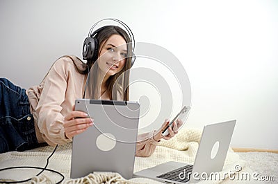 phone tablet laptop a lot of different technologies girl listens to music headphones plays phone works on computer on Stock Photo