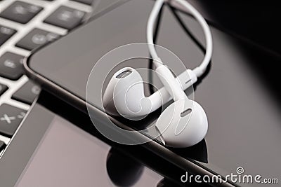 Phone and tablet with white headphones on laptop keyboard Stock Photo