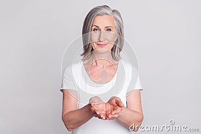 Photo of aged woman happy positive smile hold hands advert product give take isolated over grey color background Stock Photo