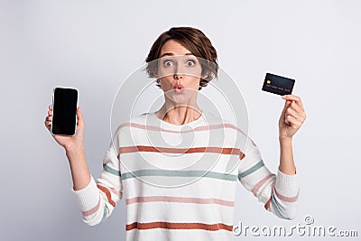 Photo of amazed funny young woman dressed striped pullover holding modern device credit card grey color Stock Photo