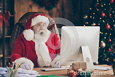 Photo of amazed santa claus sit table desk work computer impressed many wish gift list letters in house idnoors with Stock Photo