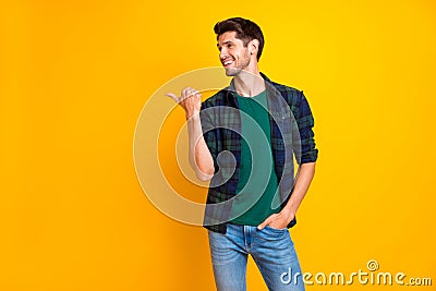 Photo of amazing guy indicating thumb finger to empty space wear casual plaid shirt and jeans isolated yellow color Stock Photo