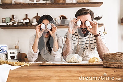 Photo of amusing couple having fun while cooking together in kitchen at home Stock Photo