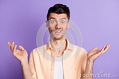 Photo of annoyed mad guy raise palms grimacing staring wear beige shirt isolated violet color background Stock Photo