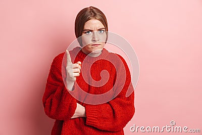 Photo of annoyed woman pointing finger upward and looking at camera Stock Photo