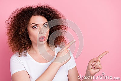 Photo of astonished woman with perming coiffure dressed white t-shirt directing at discount empty space isolated on pink Stock Photo