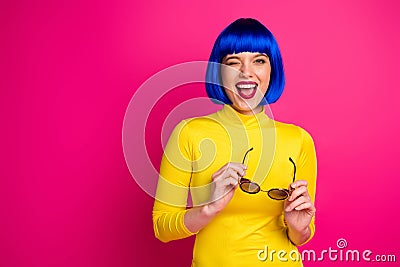 Photo of attractive funny lady modern look beaming smile blink eye hold retro specs wear stylish yellow turtleneck blue Stock Photo