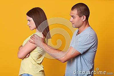 Photo of attractive woman has sad expression, stands backwards to her husband, being offended, keeps arms folded, doesnt speak to Stock Photo