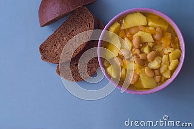 Photo bean soup in a plate and pieces of bread on a blue background. Stock Photo