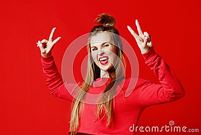 Photo of beautiful, smiling, positive girl showing peace symbol, looking at camera, posing on colorful background. Stock Photo