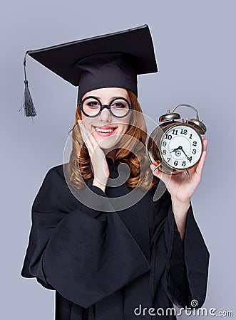 photo of beautiful young alumnus with alarm clock on the wonderful grey studio background Stock Photo