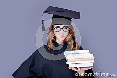 photo of beautiful young alumnus with pile of books on the wonderful grey studio background Stock Photo