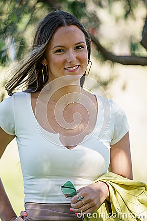 Photo of a beautiful Young woman in her early 30s posing outdoors with jacket hung over her arm Stock Photo