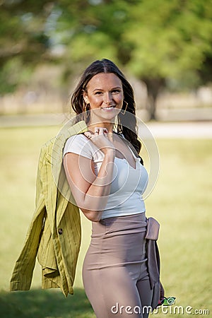 Photo of a beautiful Young woman in her early 30s posing outdoors with jacket hung over her arm Stock Photo