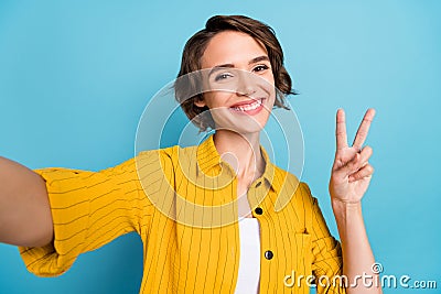 Photo of blogger lady take selfie show v-sign toothy smile wear yellow shirt isolated blue color background Stock Photo